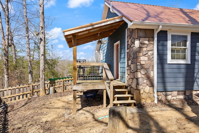 view of side of home with fence and stone siding