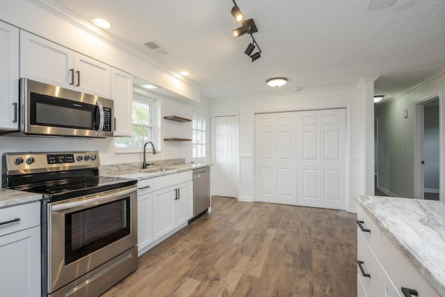 kitchen featuring wood finished floors, visible vents, a sink, stainless steel appliances, and white cabinets