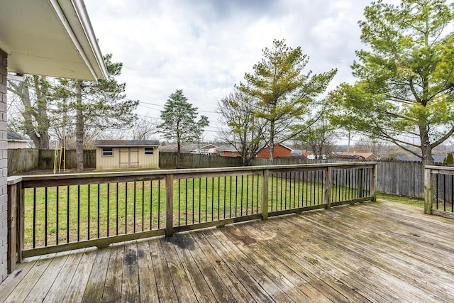 deck with a fenced backyard, an outdoor structure, and a yard