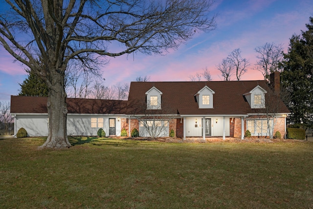 view of front of property featuring brick siding, a chimney, and a front lawn