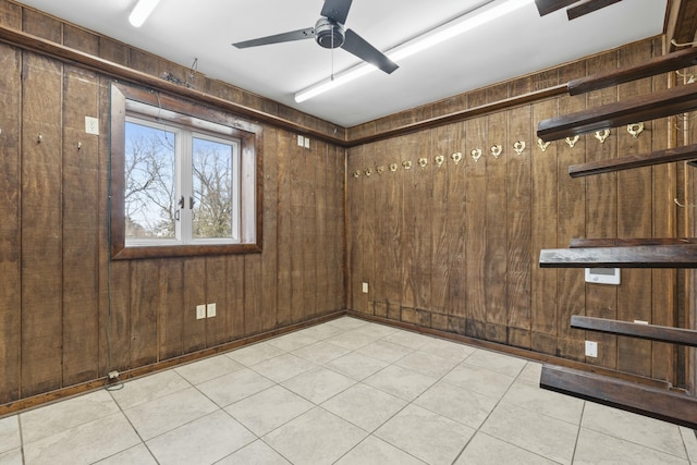 unfurnished room with light tile patterned floors, wooden walls, and a ceiling fan