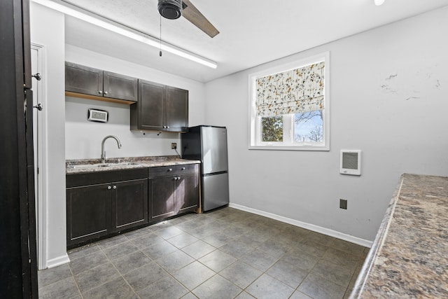 kitchen with baseboards, ceiling fan, dark brown cabinetry, freestanding refrigerator, and a sink