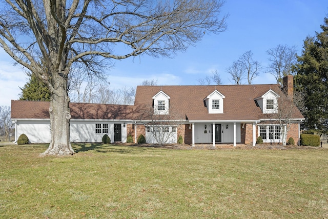 cape cod-style house featuring a front lawn, french doors, brick siding, and a chimney