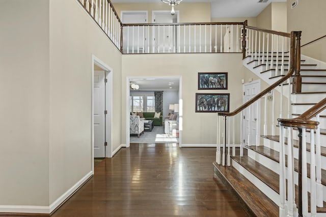 foyer featuring stairway, baseboards, a towering ceiling, and hardwood / wood-style floors