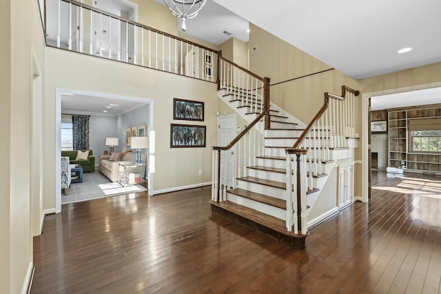 staircase featuring a wealth of natural light, a high ceiling, baseboards, and hardwood / wood-style floors