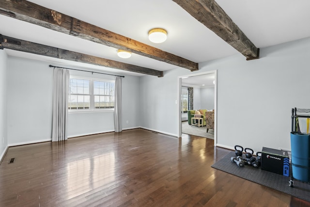 interior space with beam ceiling, wood finished floors, visible vents, and baseboards