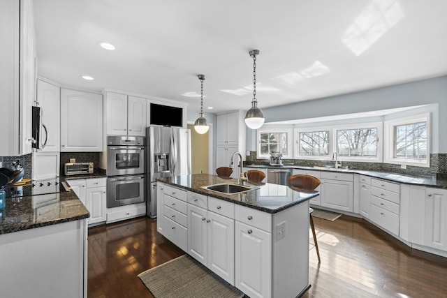 kitchen featuring a sink, tasteful backsplash, appliances with stainless steel finishes, and dark wood finished floors