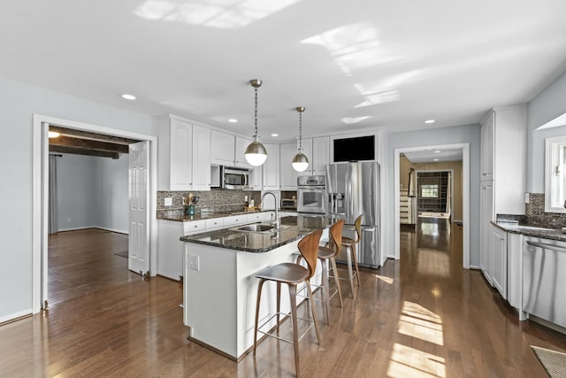 kitchen with a sink, an island with sink, dark wood-style floors, and stainless steel appliances