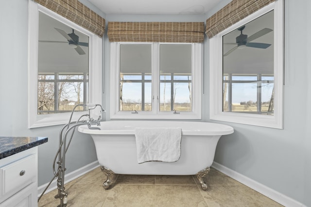 bathroom with vanity, a soaking tub, baseboards, and ceiling fan