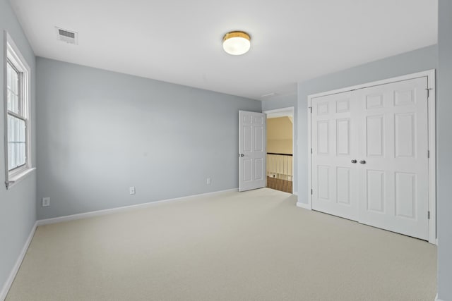 unfurnished bedroom featuring visible vents, baseboards, a closet, and carpet flooring