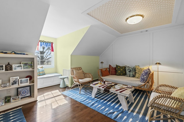 interior space with visible vents, wood-type flooring, wainscoting, a decorative wall, and lofted ceiling