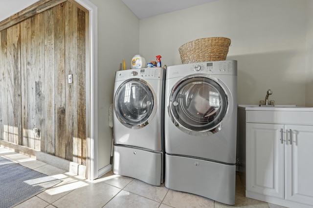 laundry area with cabinet space, light tile patterned floors, washer and dryer, and a sink