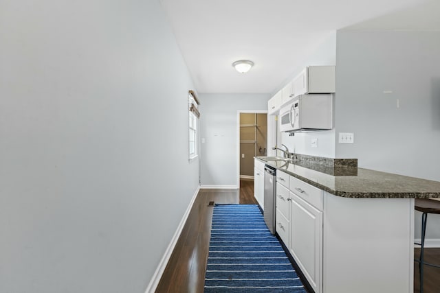 kitchen with stainless steel dishwasher, a breakfast bar area, dark wood finished floors, and white cabinetry