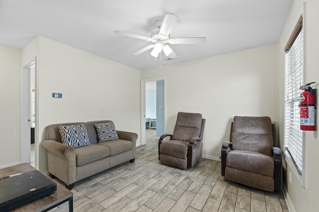 living room with light wood finished floors, baseboards, and ceiling fan