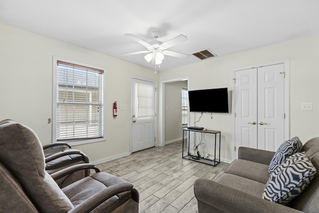 living room with light wood finished floors, visible vents, baseboards, and ceiling fan