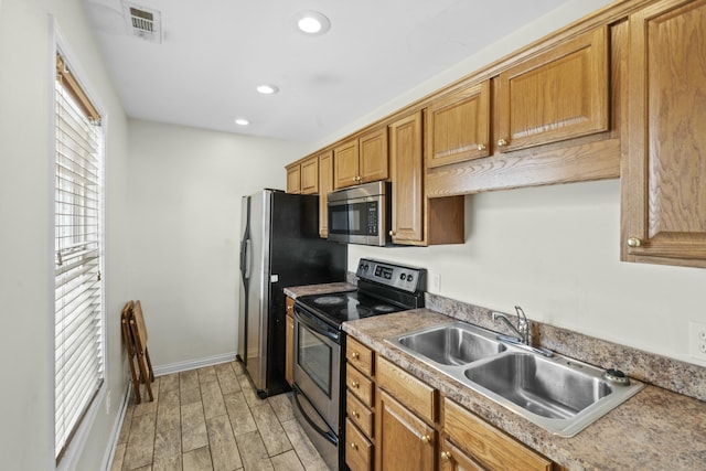 kitchen featuring visible vents, wood tiled floor, a sink, appliances with stainless steel finishes, and brown cabinets