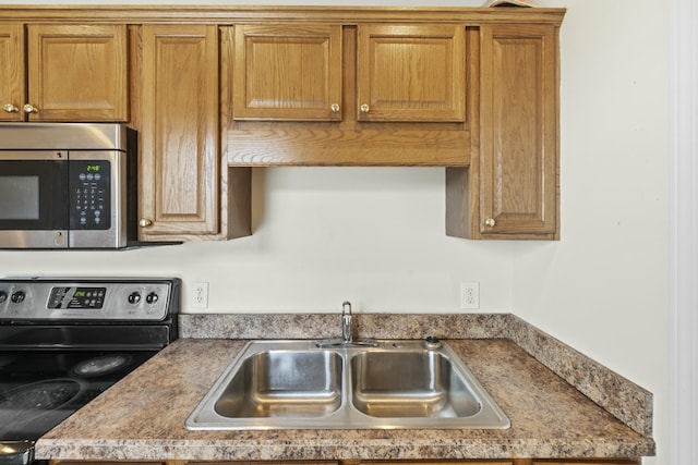 kitchen featuring brown cabinetry, appliances with stainless steel finishes, and a sink