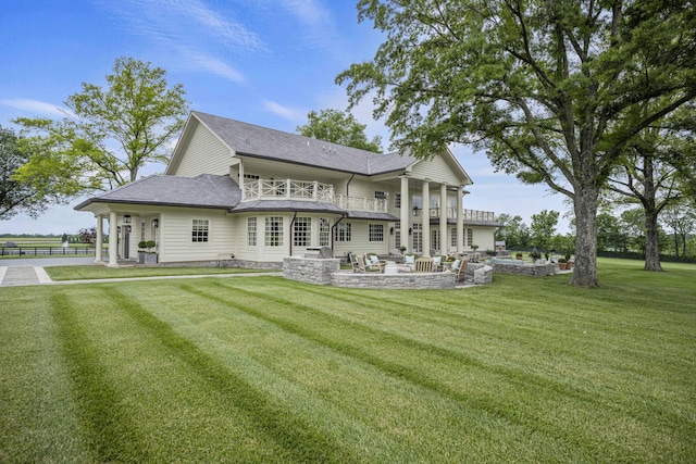 back of house featuring a lawn, a shingled roof, a balcony, and a patio area