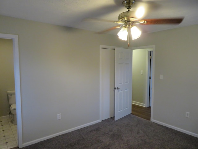 unfurnished bedroom with carpet, baseboards, a closet, ensuite bath, and a ceiling fan