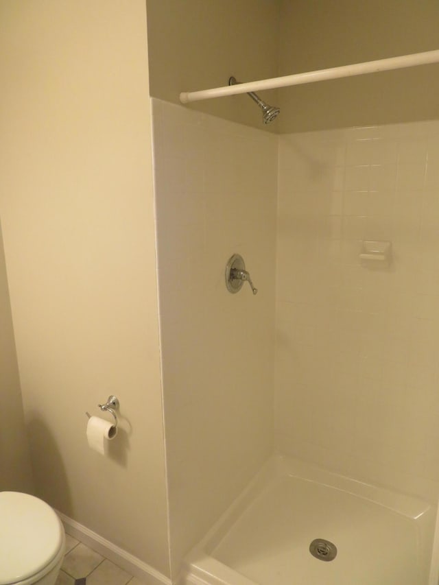 full bathroom featuring baseboards, toilet, a stall shower, and tile patterned flooring