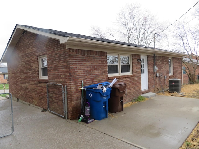 rear view of house with brick siding, central air condition unit, entry steps, and a patio