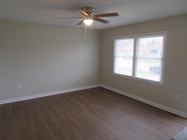 empty room featuring visible vents, a ceiling fan, baseboards, and dark wood-style flooring