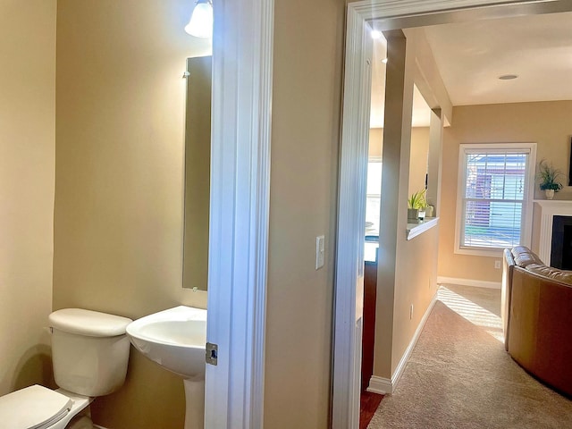 half bath featuring toilet, a fireplace, and baseboards