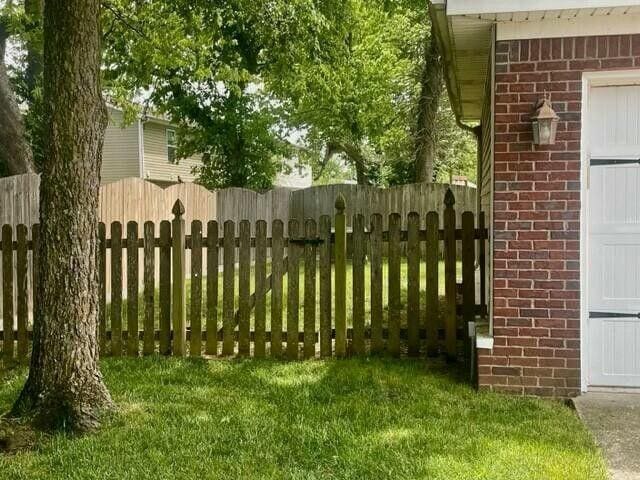 view of gate with fence and a lawn