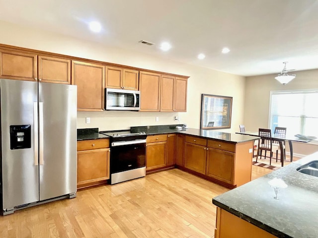 kitchen with visible vents, a peninsula, recessed lighting, stainless steel appliances, and light wood-type flooring