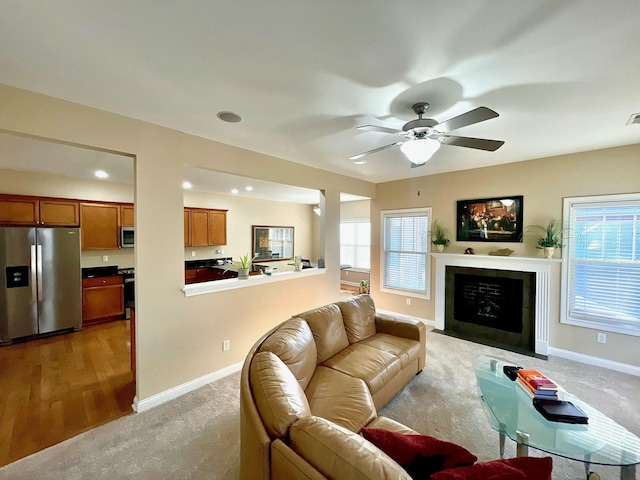 living room featuring a wealth of natural light, baseboards, a fireplace with flush hearth, and a ceiling fan