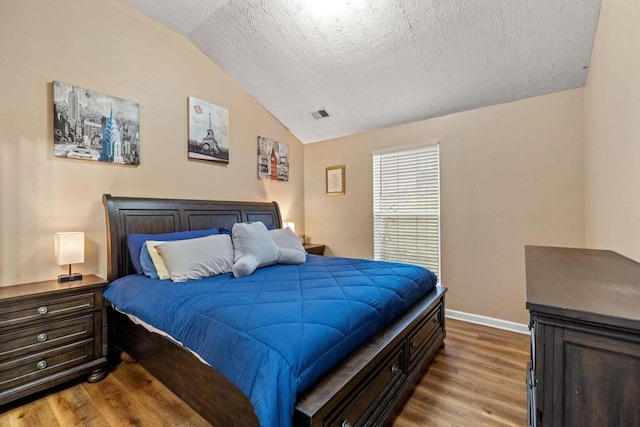 bedroom featuring baseboards, a textured ceiling, wood finished floors, and vaulted ceiling