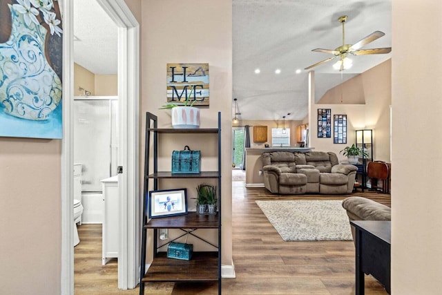 living room featuring vaulted ceiling, baseboards, ceiling fan, and wood finished floors