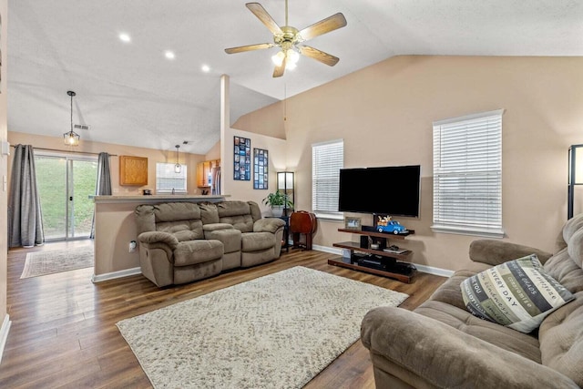 living area with visible vents, baseboards, vaulted ceiling, wood finished floors, and a ceiling fan