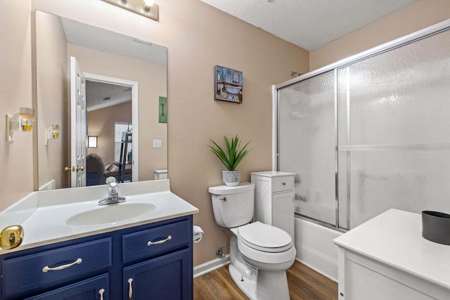 bathroom with toilet, wood finished floors, shower / bath combination with glass door, a textured ceiling, and vanity