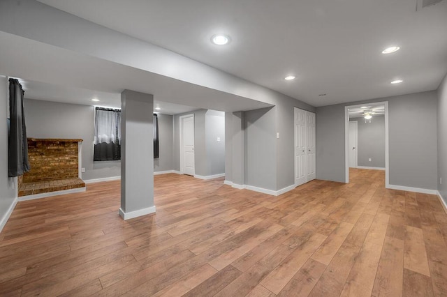 finished basement with baseboards, light wood finished floors, and ceiling fan