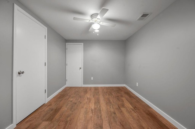 empty room featuring visible vents, wood finished floors, baseboards, and ceiling fan