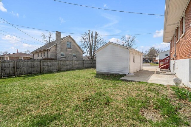 view of yard featuring a patio, an outdoor structure, and a fenced backyard