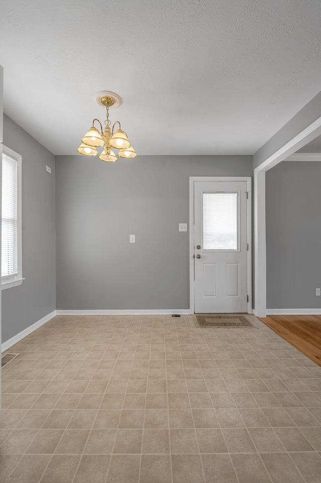 empty room featuring visible vents, baseboards, and an inviting chandelier