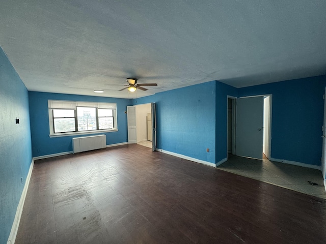 unfurnished room featuring baseboards, radiator heating unit, ceiling fan, and wood finished floors