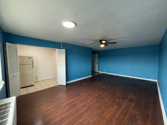 spare room with wood finished floors, a ceiling fan, and baseboards