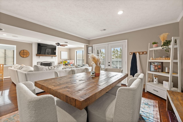 dining area with dark wood-style flooring, visible vents, ornamental molding, a ceiling fan, and french doors