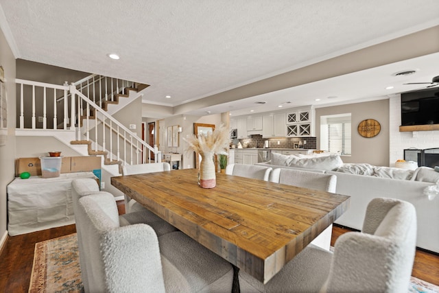 dining area with crown molding, stairway, recessed lighting, dark wood-style floors, and a fireplace