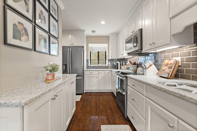 kitchen featuring stainless steel appliances, white cabinetry, light stone counters, dark wood-style floors, and backsplash