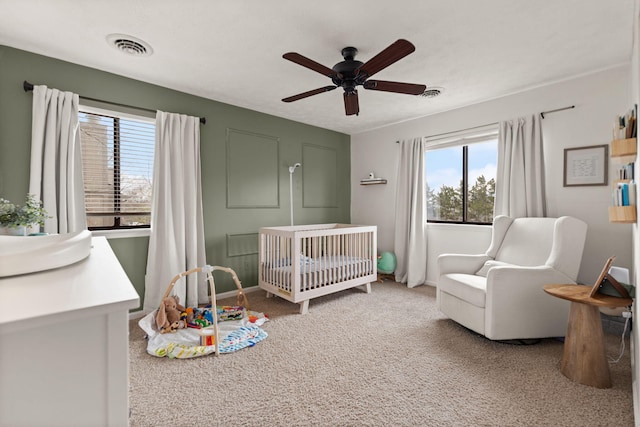bedroom featuring carpet flooring, ceiling fan, visible vents, and a nursery area