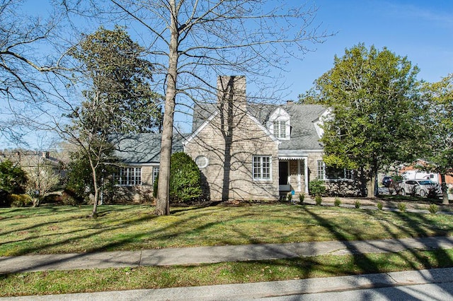 cape cod-style house with a chimney and a front yard