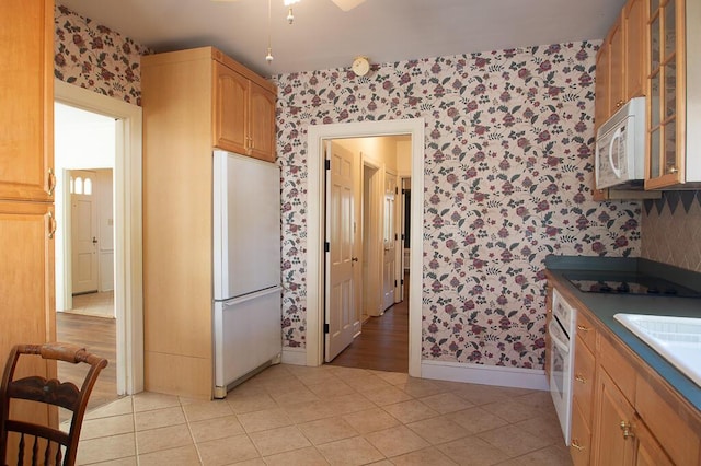 kitchen with baseboards, white appliances, wallpapered walls, and glass insert cabinets