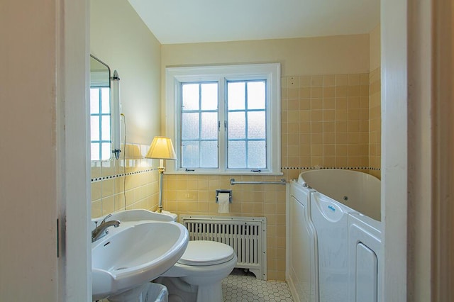full bathroom with a sink, separate washer and dryer, tile walls, radiator, and tile patterned flooring