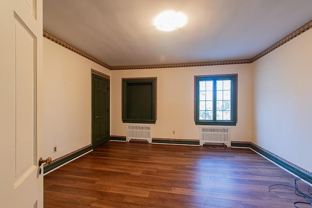 empty room featuring dark wood finished floors, radiator, and baseboards