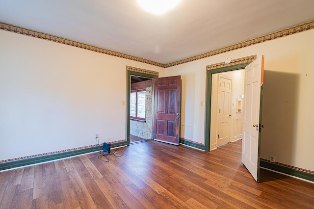 spare room featuring wood finished floors and baseboards
