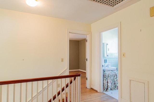 hall featuring light wood-type flooring and an upstairs landing